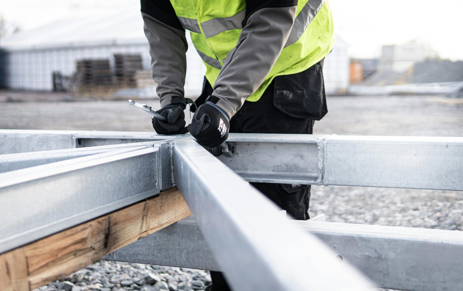 A construction worker adjusting steel beams outdoors for a building framework.